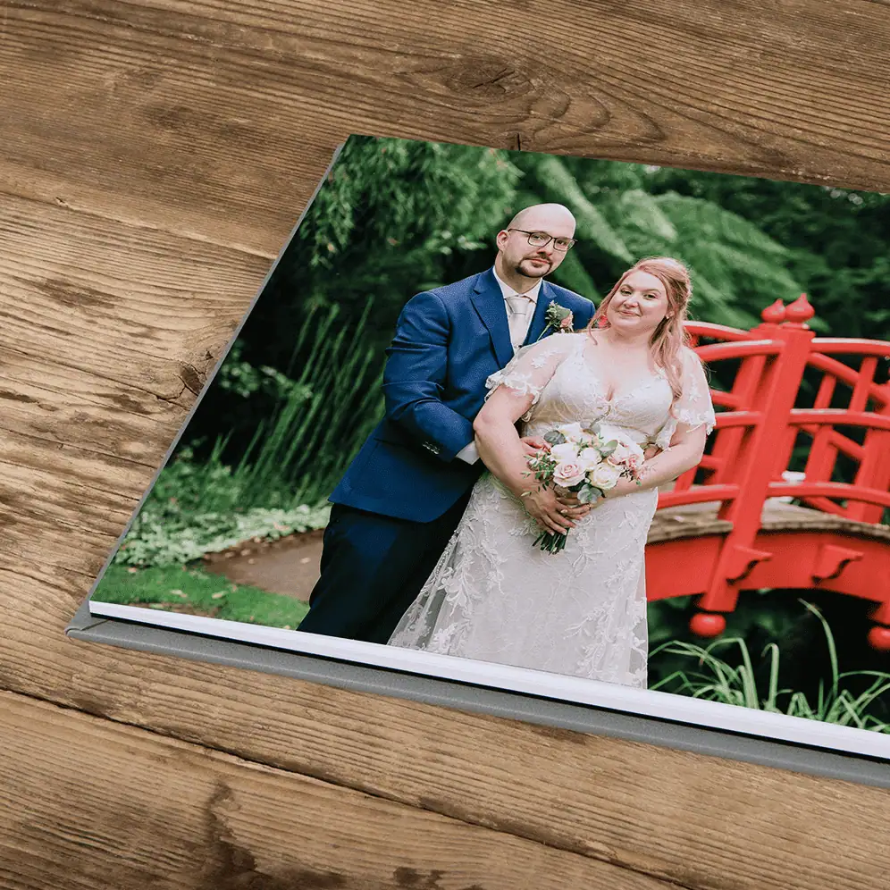 Wedding couple portrait in a lush garden with a red bridge, captured by Paul Phipps-Williams Photogr.
