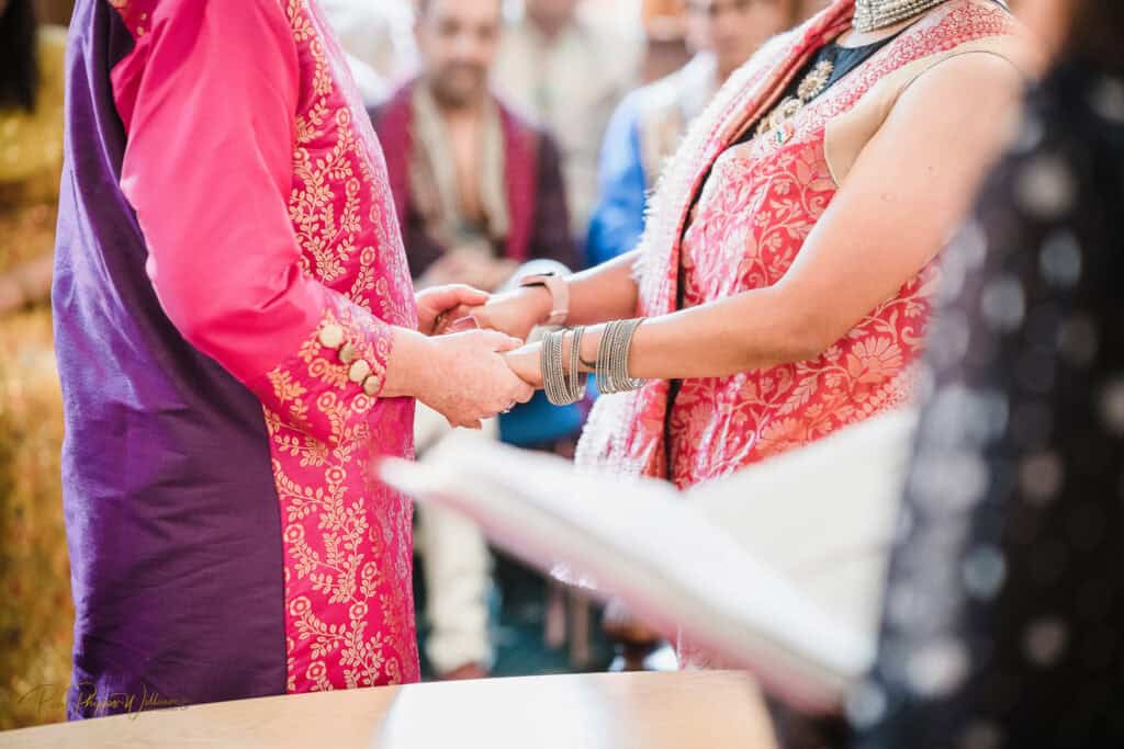 two brides hold hands in their wedding service